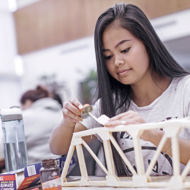 A student experiments with elements of engineering and science to construct a scale-model bridge in the Mary F. Shipper Library.
