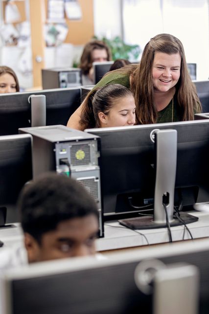 An instructor teaching a student about Business Administration in a computer lab. 