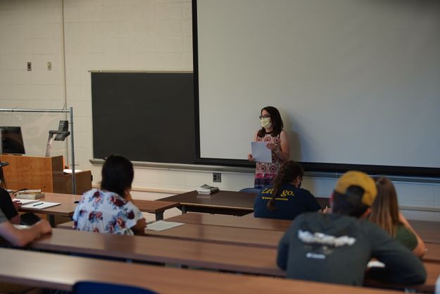 Donning a mask, History Professor Cassandra Pritts reviews her syllabus with students, who are also required to mask up and implement physical distancing