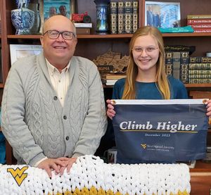 Chris Gilmer posing for a photo with Alexandrea Kile, who is holding the catamounts climb higher banner