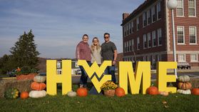 A family standing around the H-O-M-E letters on campus